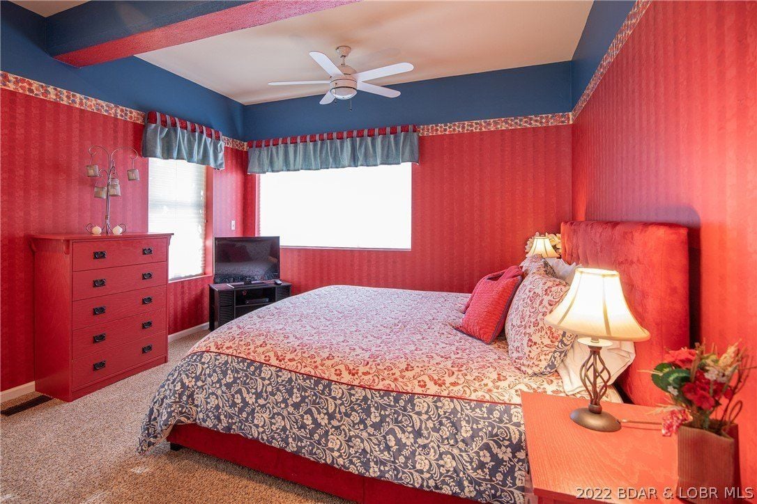 The guest bedroom features a wall-to-wall carpet and a queen-size bed giving off a cozy feel.