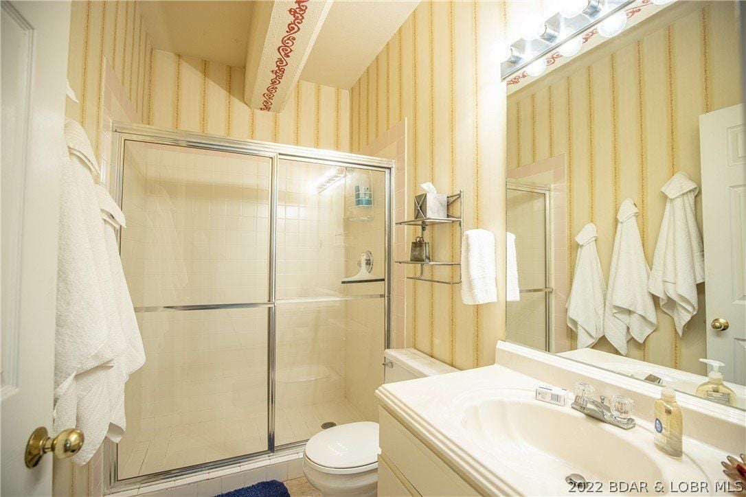The guest bathroom features a shower cubicle with a glass enclosure and a vanity with a tile countertop.