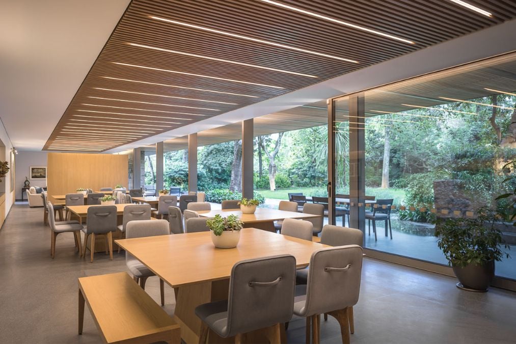The dining room in showcases multiple sets of dining tables and chairs, blending the comfort of indoor seating with the beauty and openness of the outdoors.