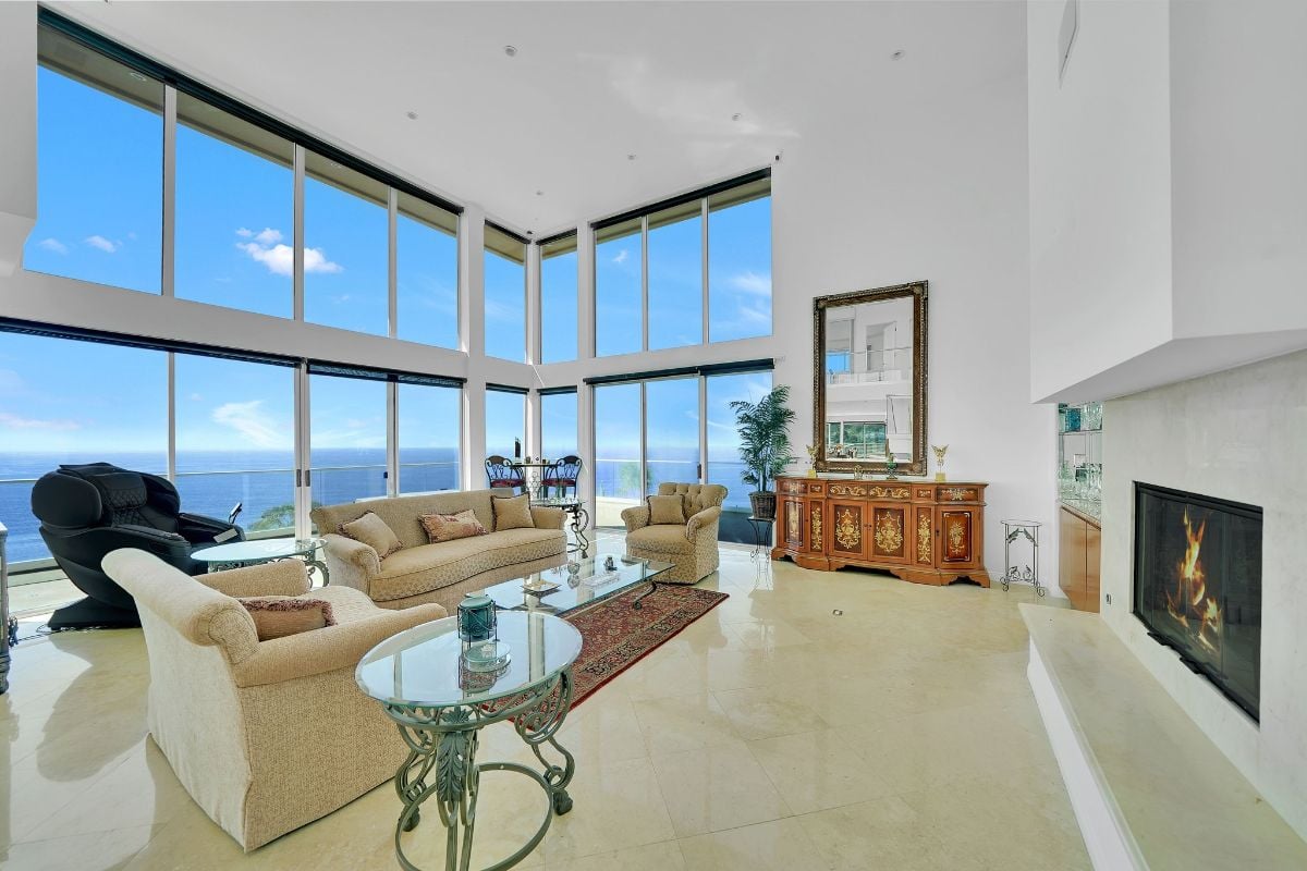 The living room features a sleek fireplace and sliding doors that open onto the spacious outdoor patio, where you can enjoy the stunning ocean view and picturesque sunsets.