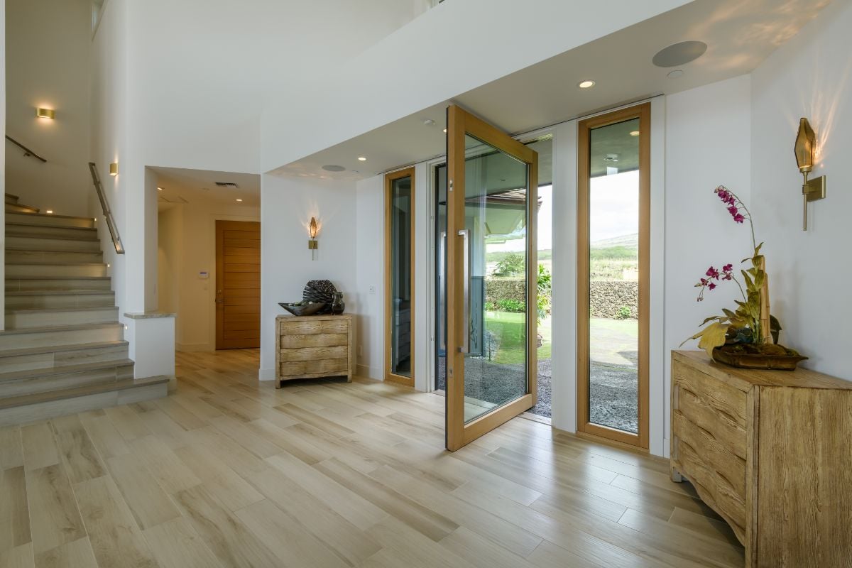 The entry features a glass door, wall lights, and wooden flooring.