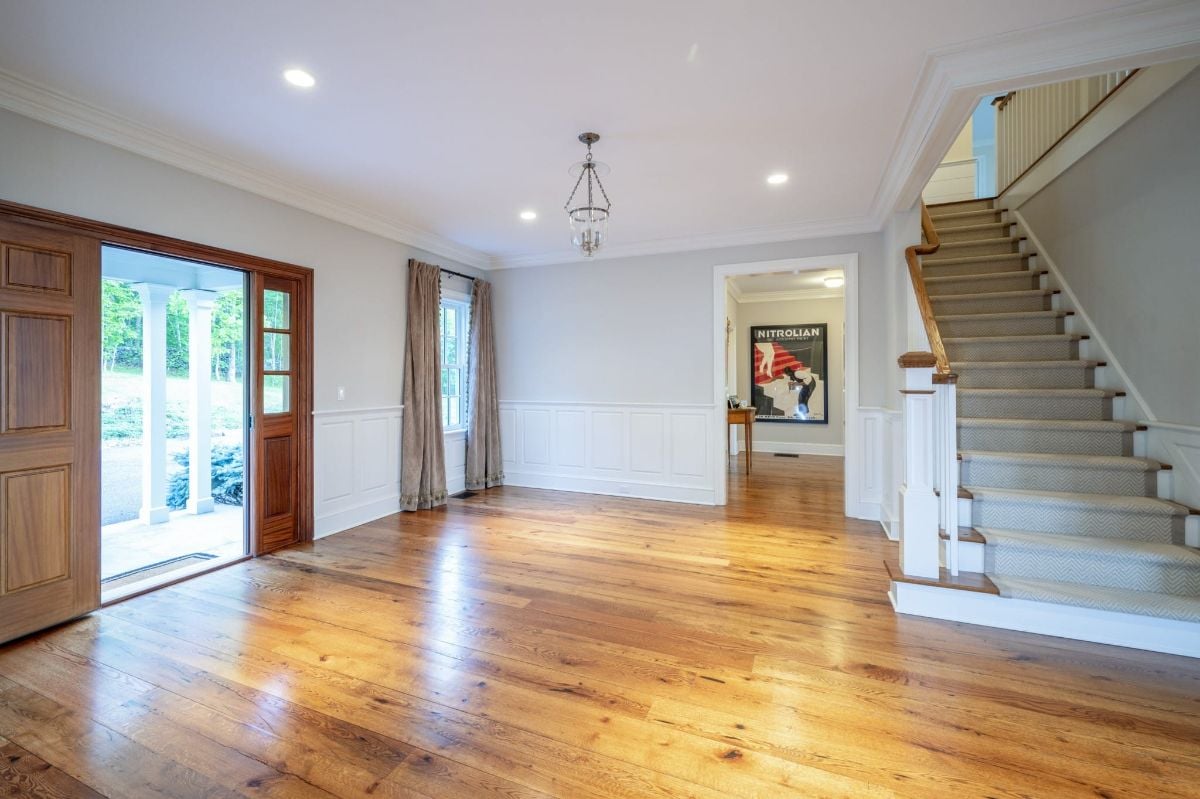 The foyer features impressive wooden double doors and an elegant straight staircase that leads to the upper floors.