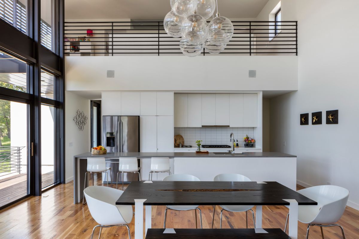 The main public space, which includes the kitchen, dining, and living areas, in a two-story wood-clad structure filled with light and a view of the lake.