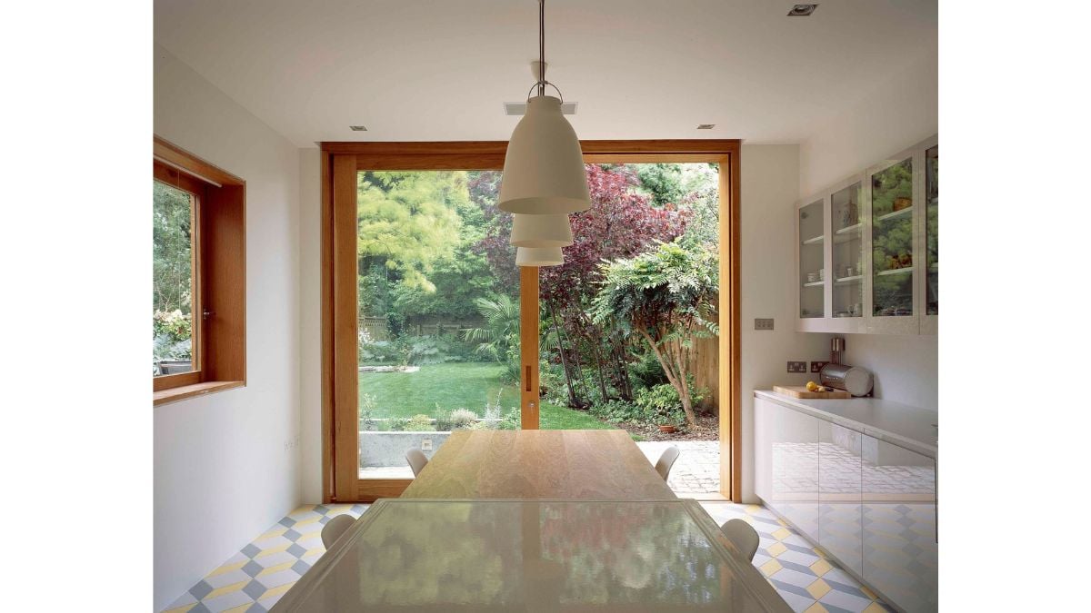 A wine cellar is hidden by an electric hatch in the kitchen floor, which is covered in a custom tessellated pattern of yellow, white, and grey tiles.