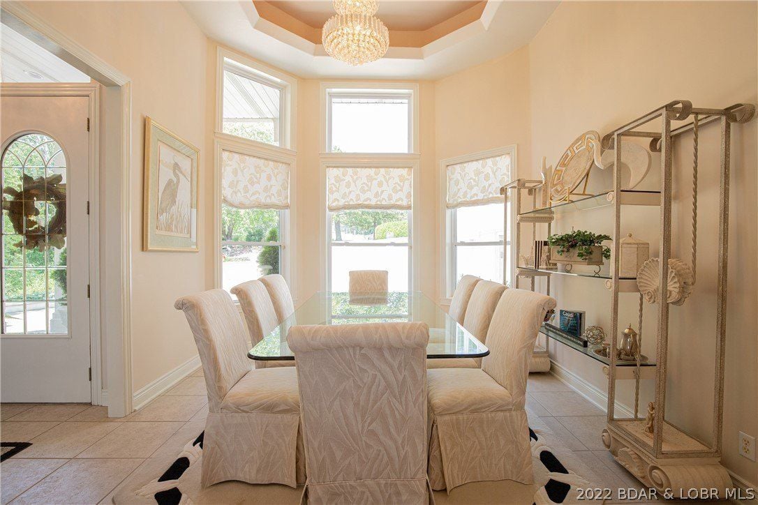 The formal dining room features a glass dining table lit by a luxurious ceiling lamp.