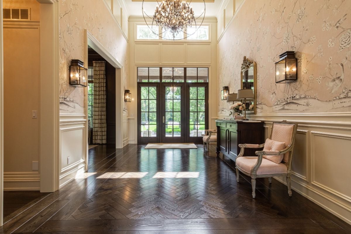 The Grand Foyer boasts oversized French Doors, extensive wainscoting & as well herringbone wood flrs, RH Light Fixtures, Schumacher & Co wallpaper.