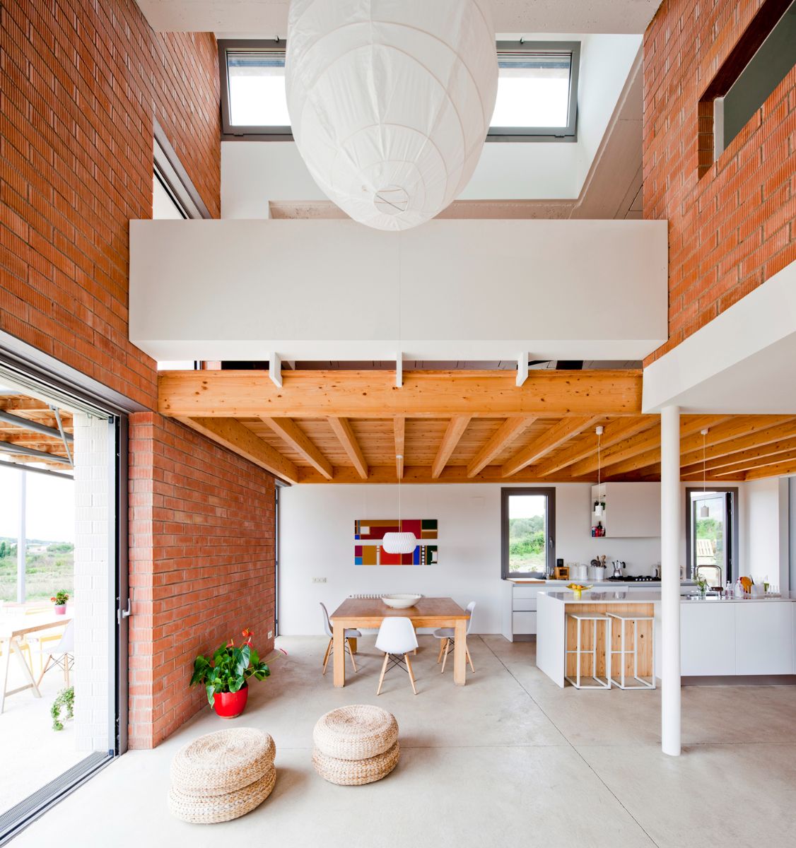 An open-concept dining and kitchen layout with wood, bricks, glass, and concrete fittings.