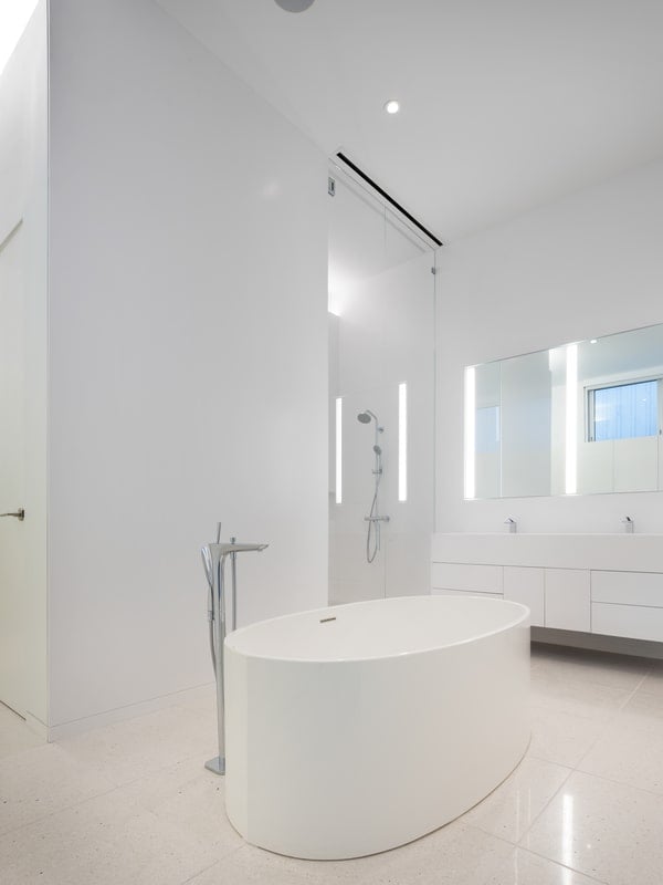 The bathroom, complete with soaking tub and walk-in shower, reflects the owner's minimalist and curated lifestyle.
