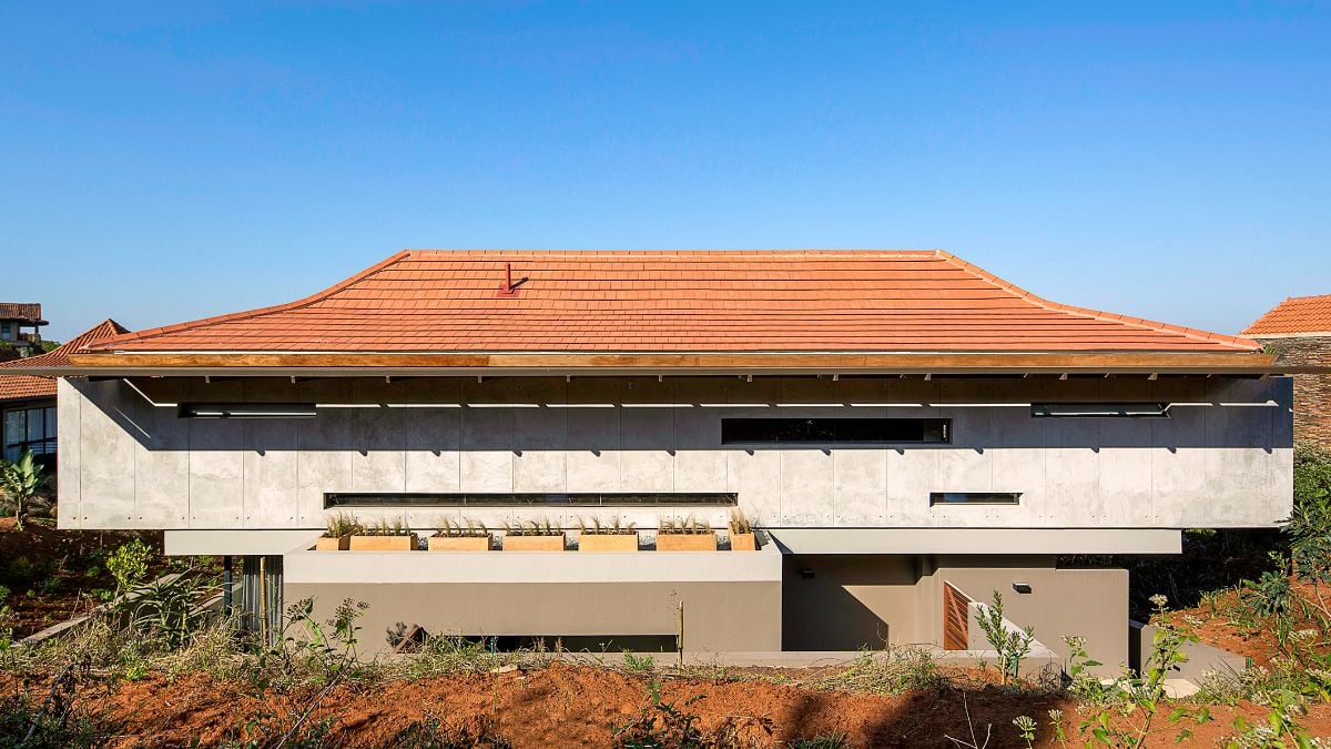 The entire length of the rear elevation and beyond the rear corners on either side of the house are covered by a monolithic raw concrete form.