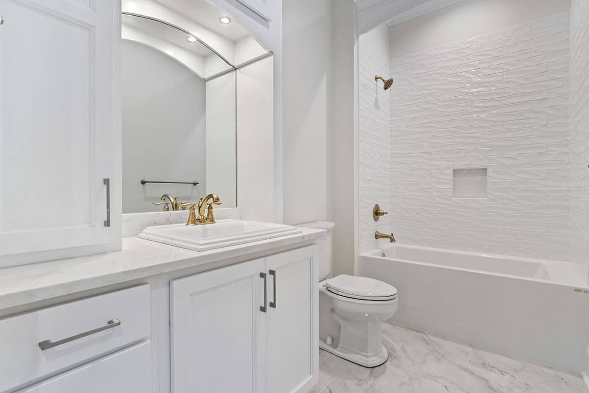 This bathroom offers a single sink vanity and a tub and shower combo fitted with brass fixtures.