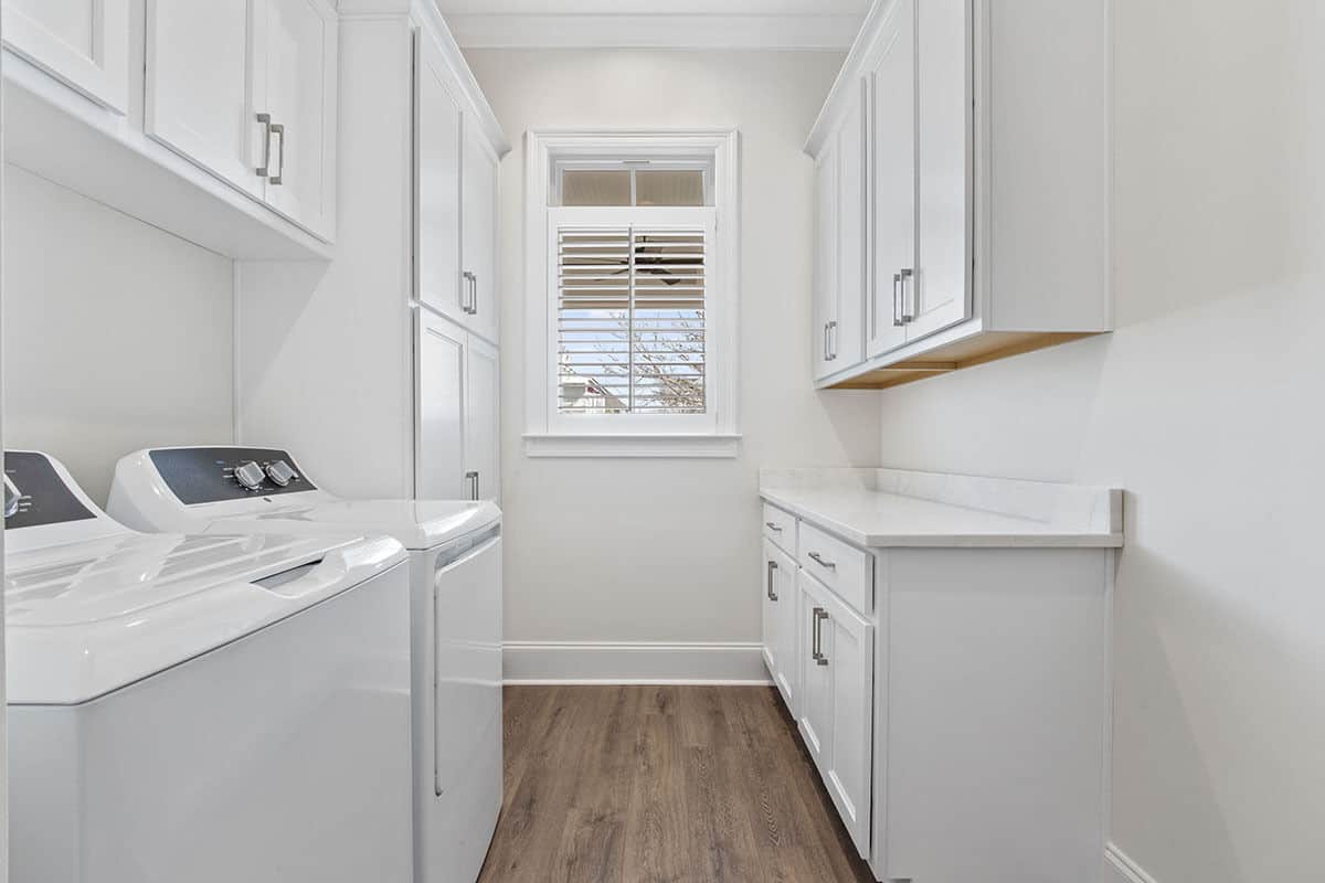 The laundry room includes additional storage and counter space along with a top-load washer and dryer.