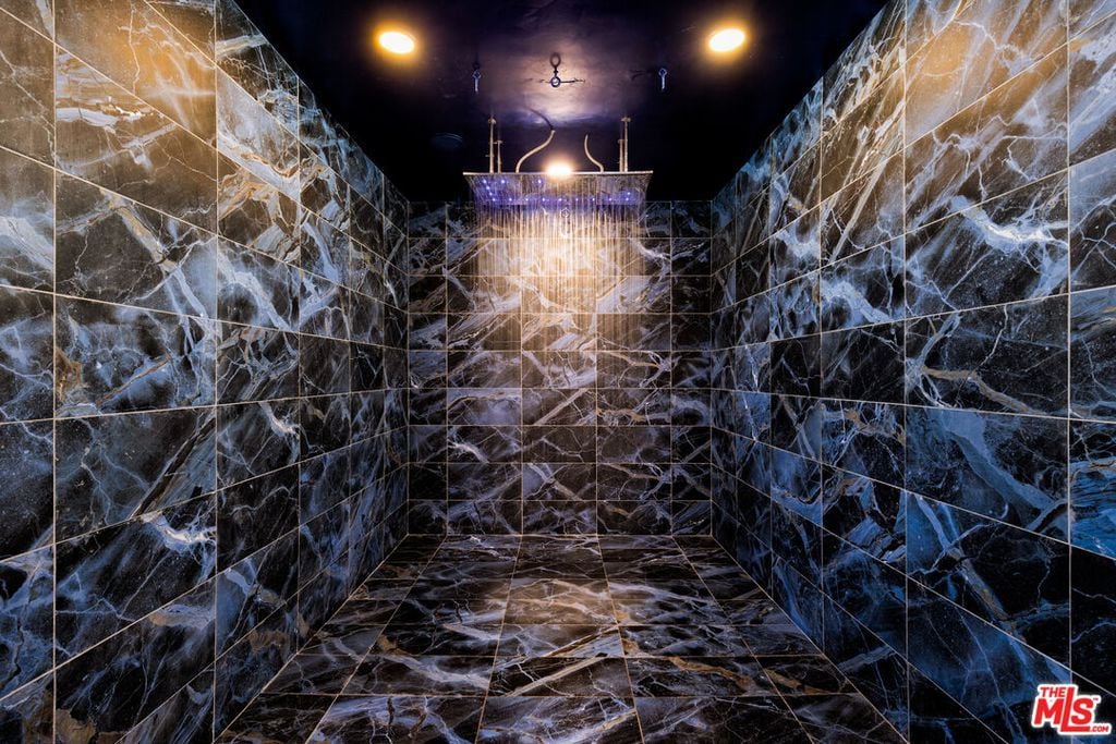 The luxurious rainfall shower in the spa-like bathroom with intricate tiling on the walls and flooring, making it a true sanctuary for relaxation.