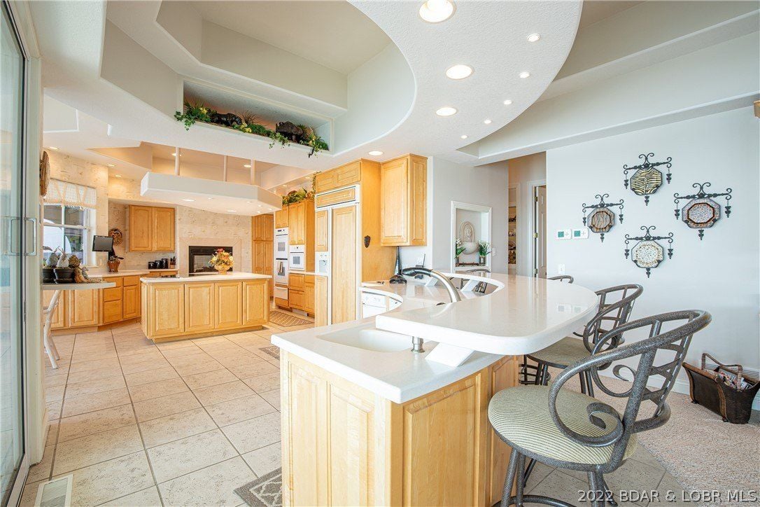 The kitchen features a bi-level kitchen island and a counter with high chairs.