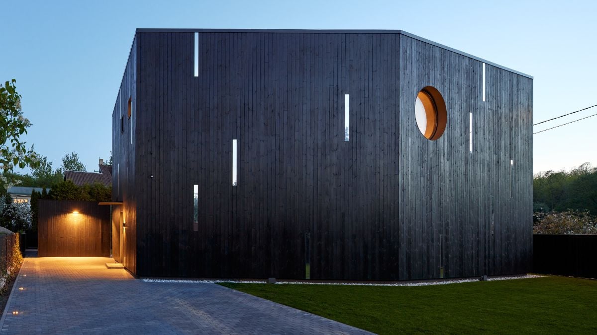 A two-story home with a modest garage volume that is the same shape as the house but scaled down to accommodate one automobile.