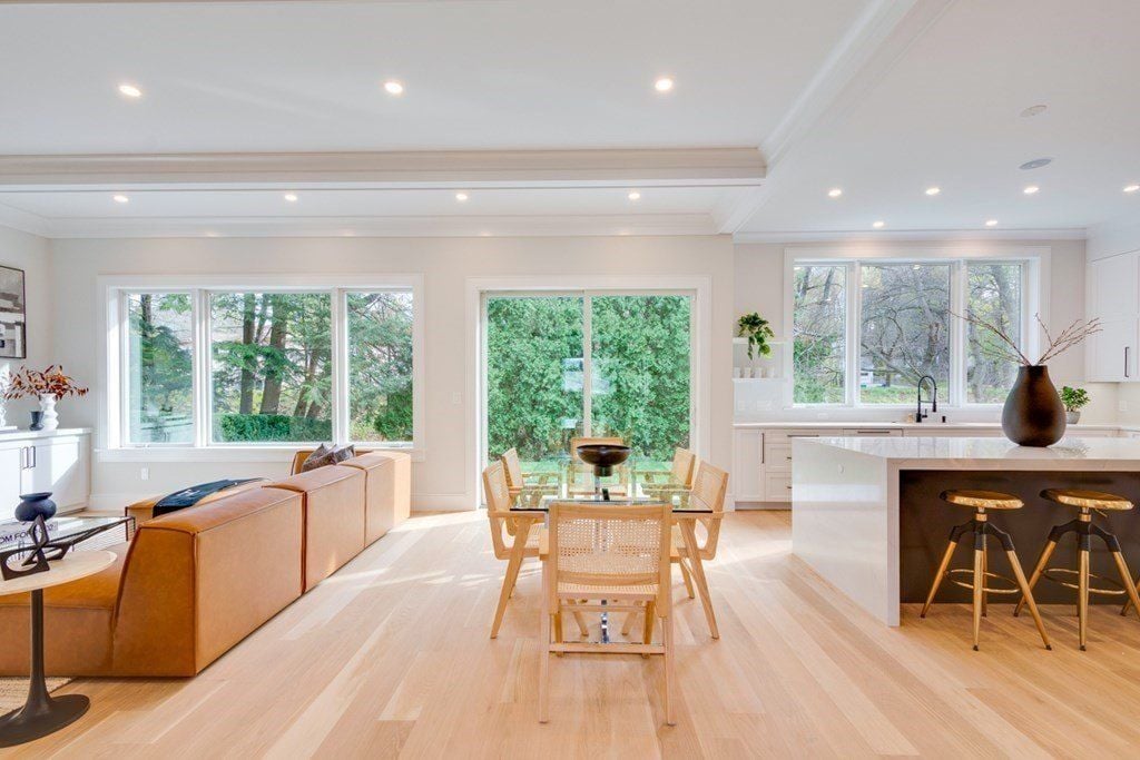 A dining table with glass tops sits next to the open kitchen.