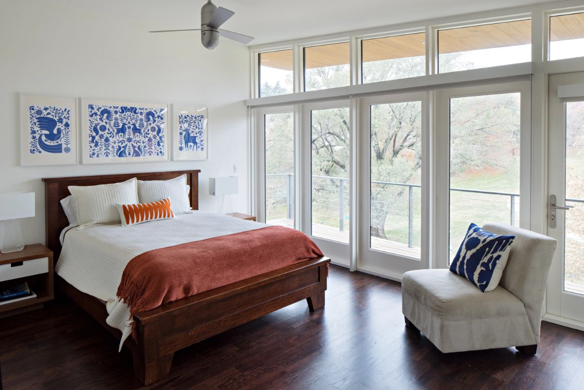 A bedroom with a balcony offering a panoramic view of the park and surrounding area.
