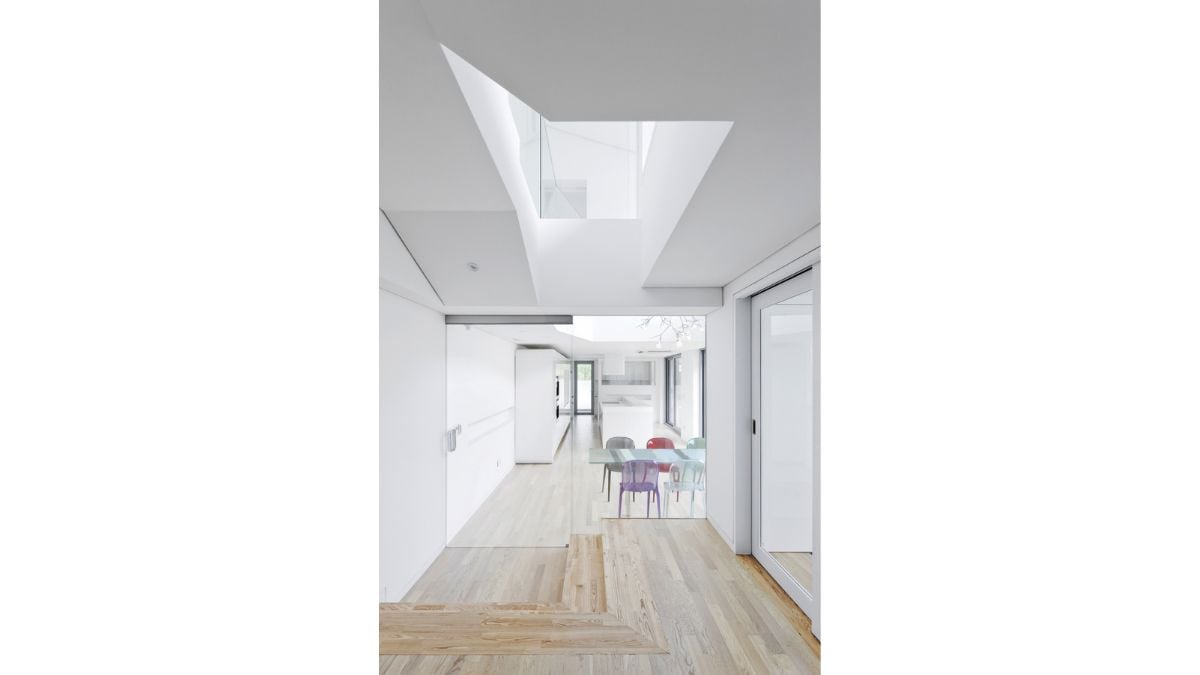 Due to the interior's all-white color scheme, the dining area's oak floor has bright features.