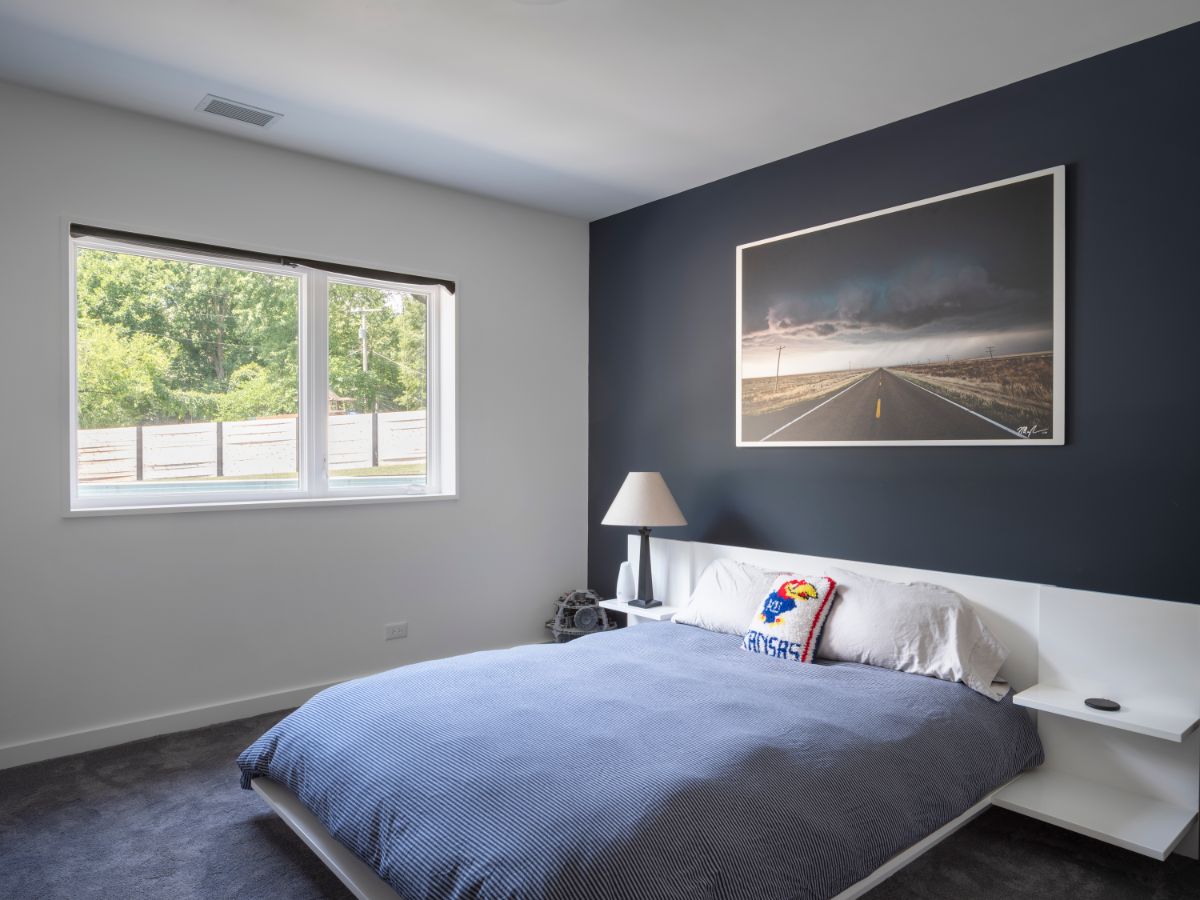 A masculine-themed bedroom featuring a floating bed with a built-in headboard and bedside tables.