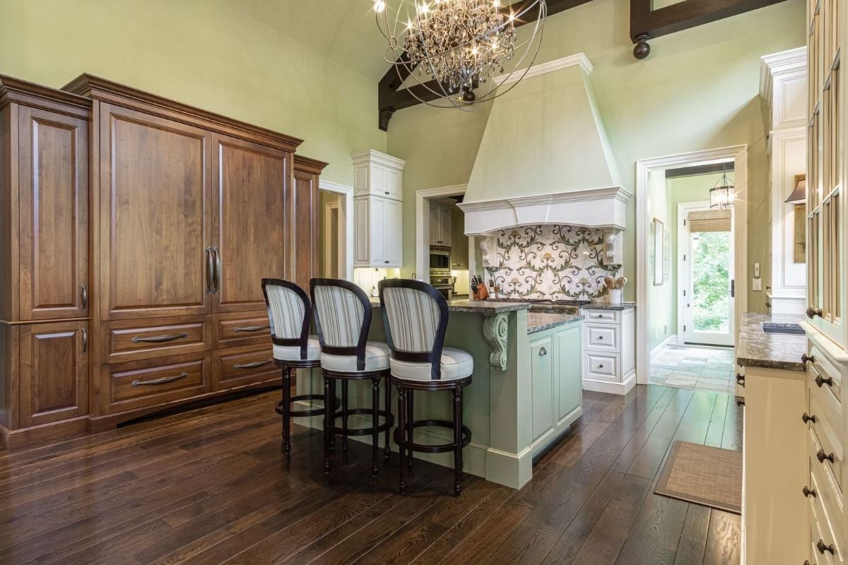 The kitchen features a bi-level kitchen island with a granite countertop and a luxurious chandelier that lit the place.