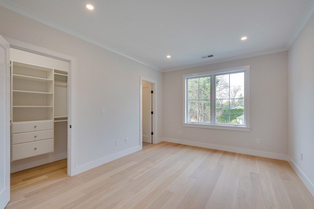 An empty room reserved for a bedroom features a walk-in closet and insulated windows.