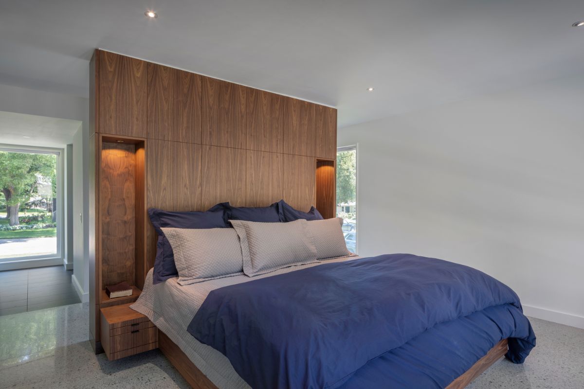 A light and airy bedroom with drawers for storage, a headboard, and huge windows and doors.