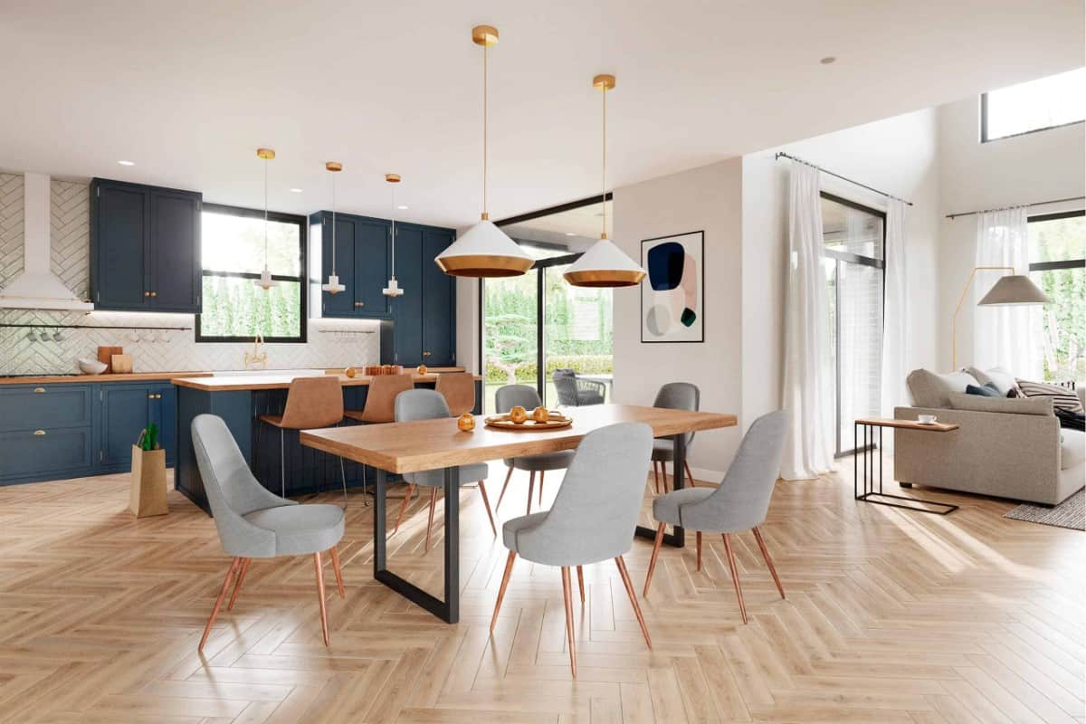 Combined kitchen and dining area with dark blue cabinets, a center island, and a modern dining set topped with brass pendants.