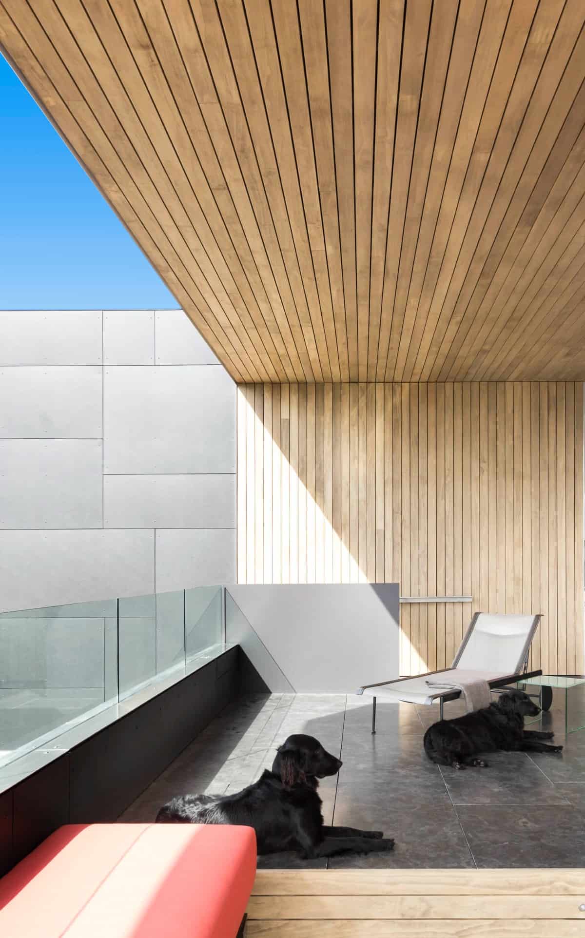 The balcony has tiled flooring, glass railings, and a wood-paneled accent wall that extends to the ceiling providing warmth and comfort.