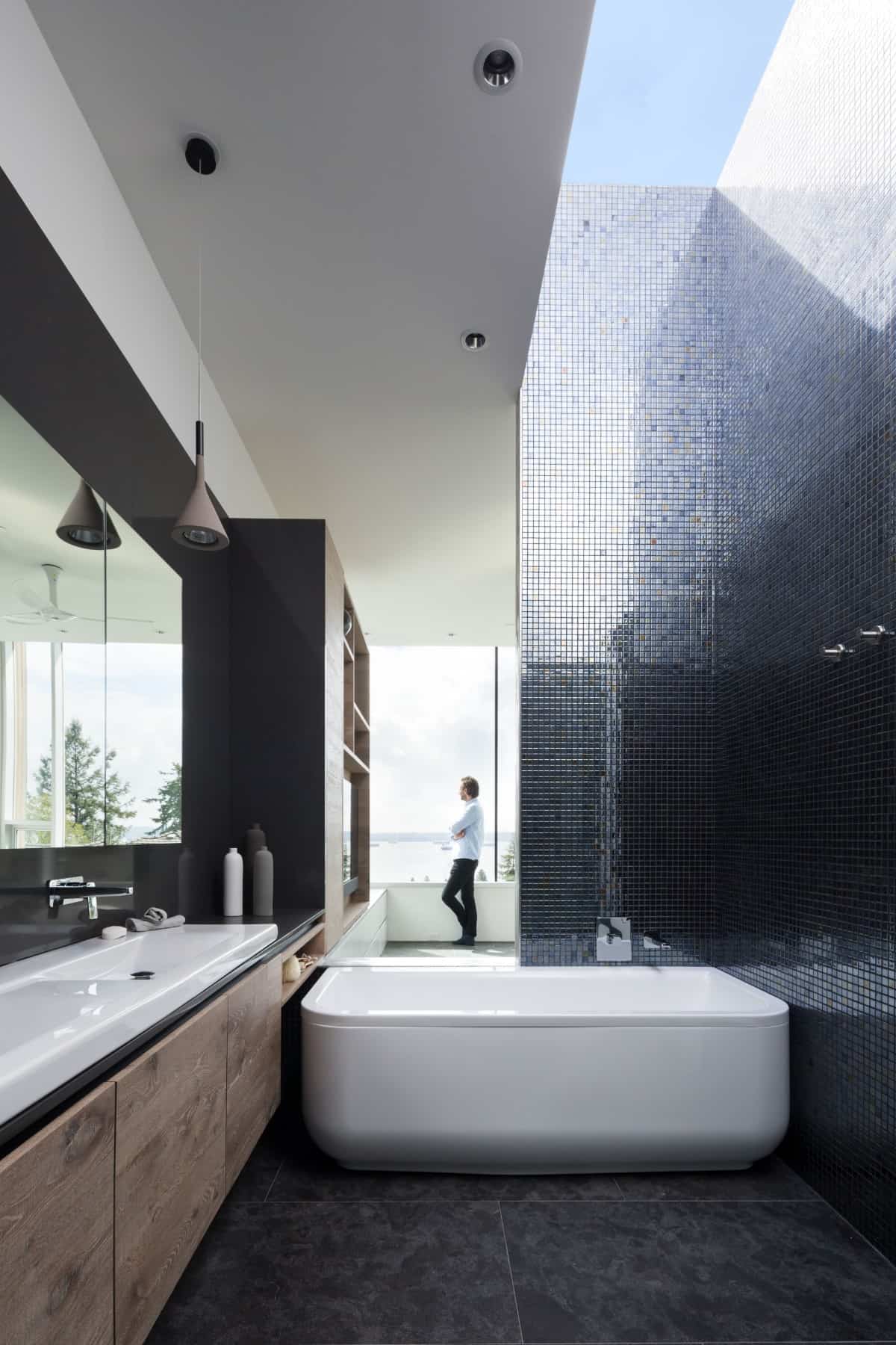 The primary bathroom offers a large vanity and a deep soaking tub illuminated by a linear skylight.