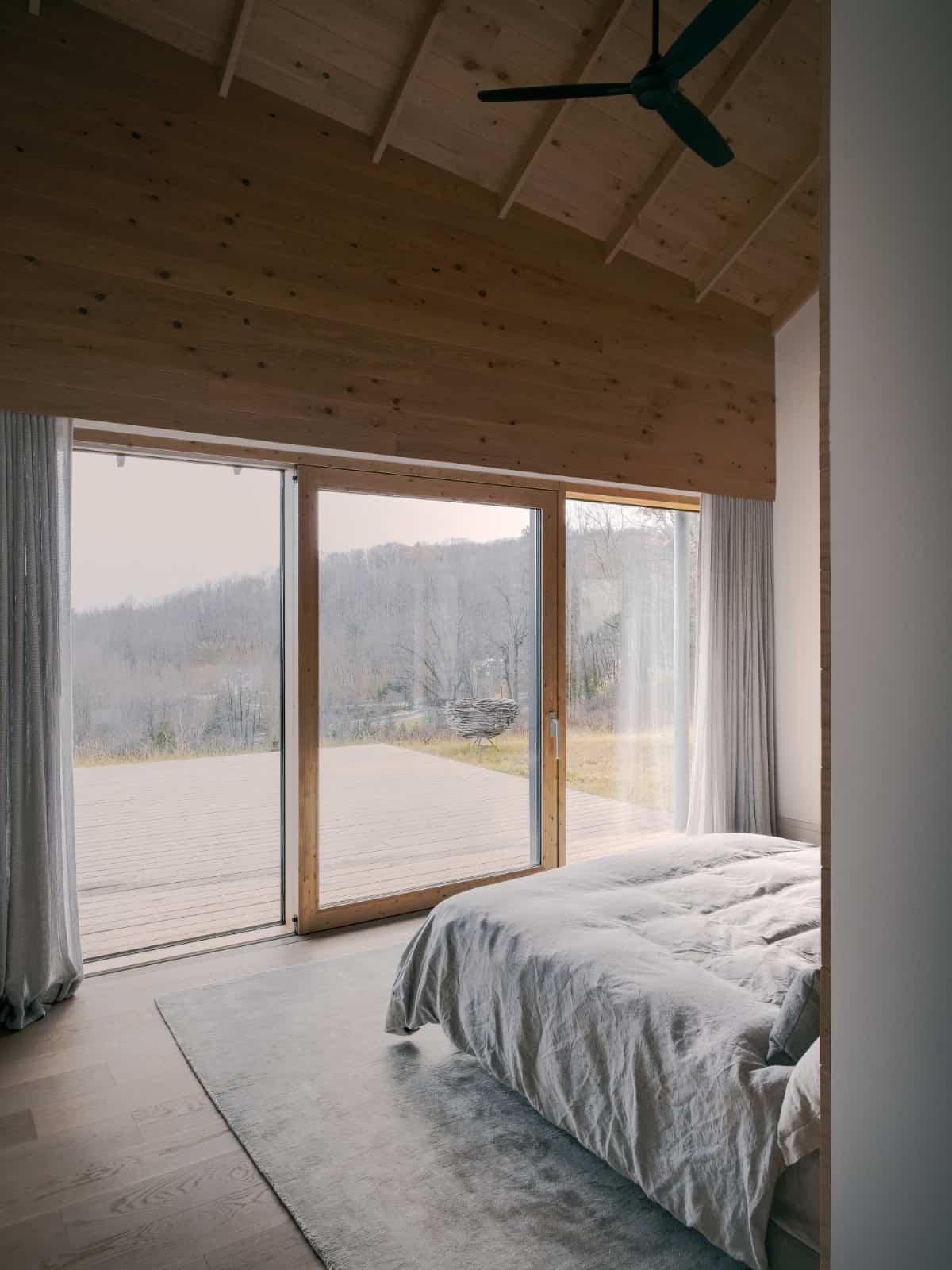 Light wood planks that run from the flooring through the walls and ceiling create a cozy ambiance in this bedroom.