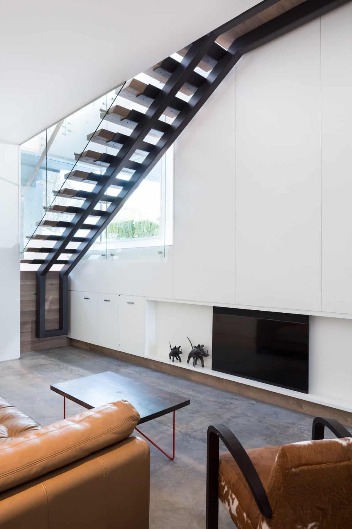 This living area features built-in cabinets and a fireplace under a modern staircase.