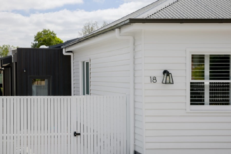 The house's front facade, which is made up of white and black timber cladding.