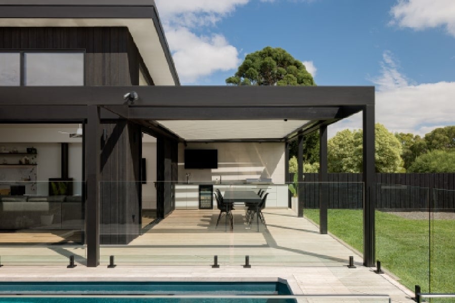 The exterior facade, complete with a modern pergola and a view of the surrounding trees.