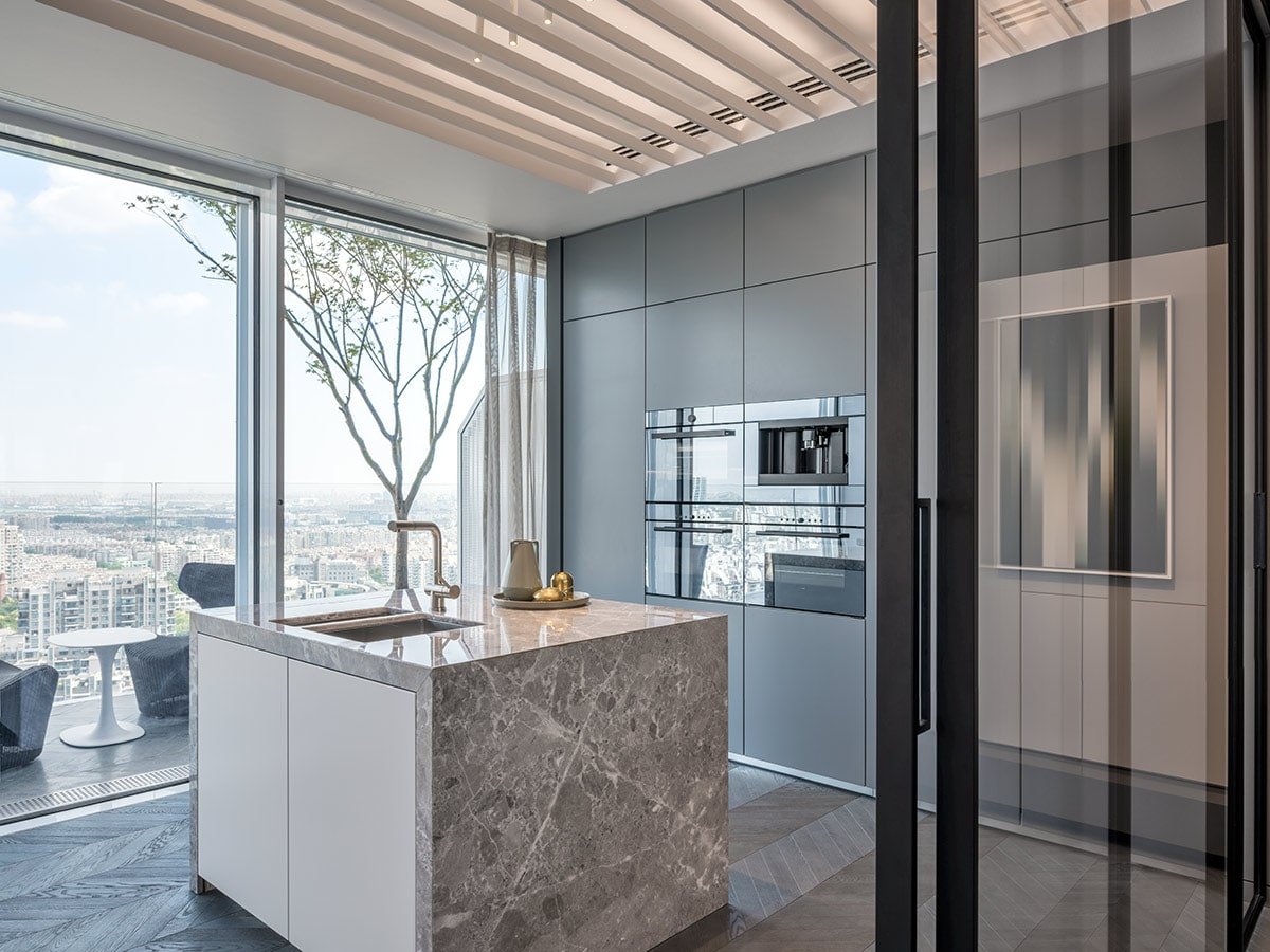 The island is likewise covered in grained Chinese marble, and the kitchen is outfitted with high-end appliances.