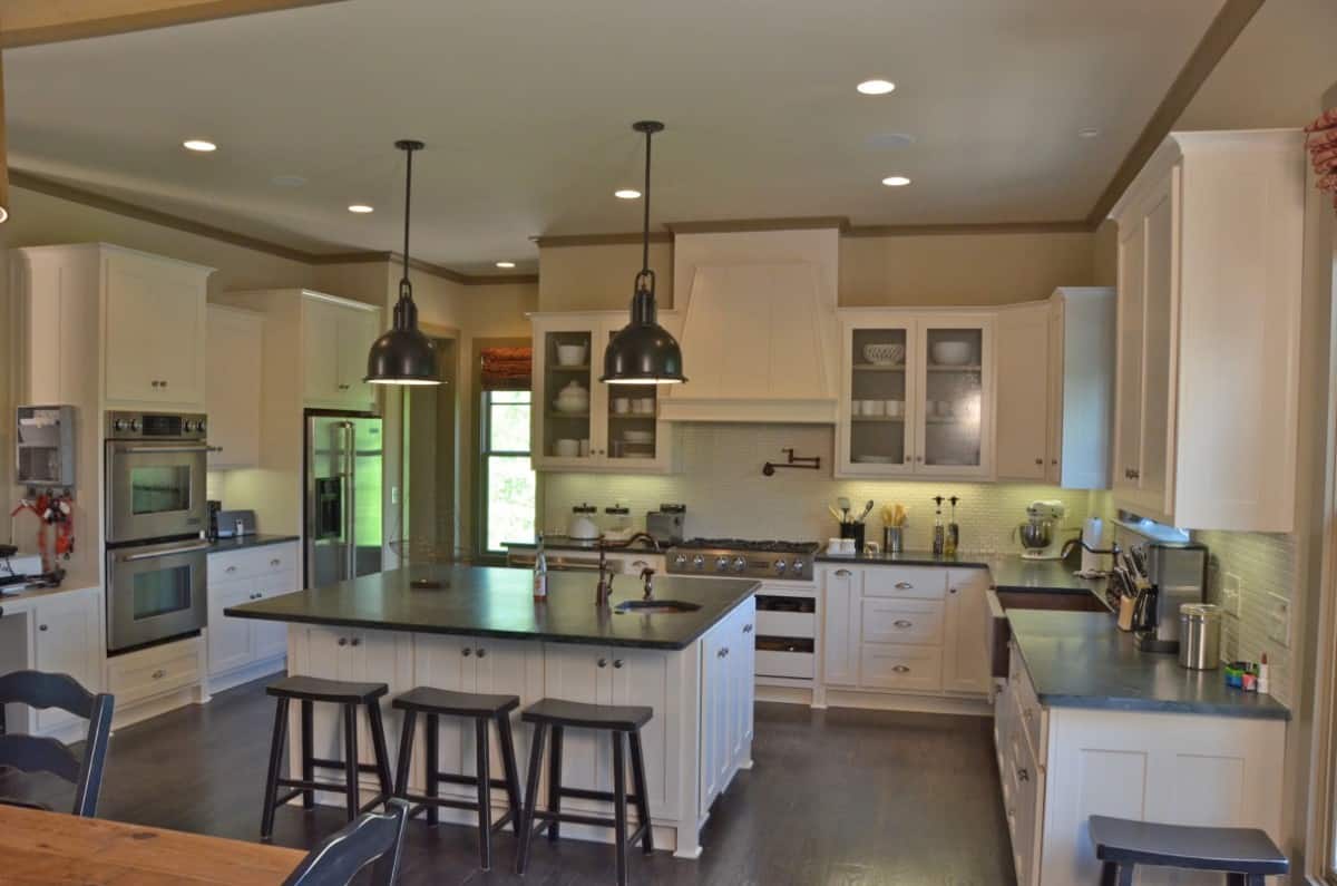 The kitchen is equipped with stainless steel appliances, white cabinetry, multiple sinks, and a breakfast island.