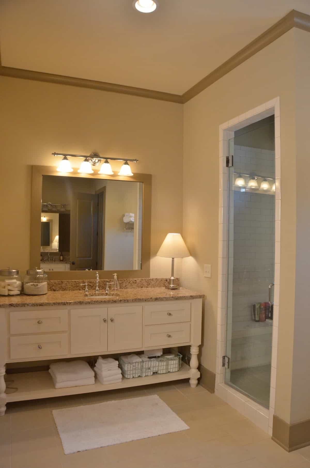 A white vanity with a granite countertop and a wooden framed mirror completes the primary bathroom.