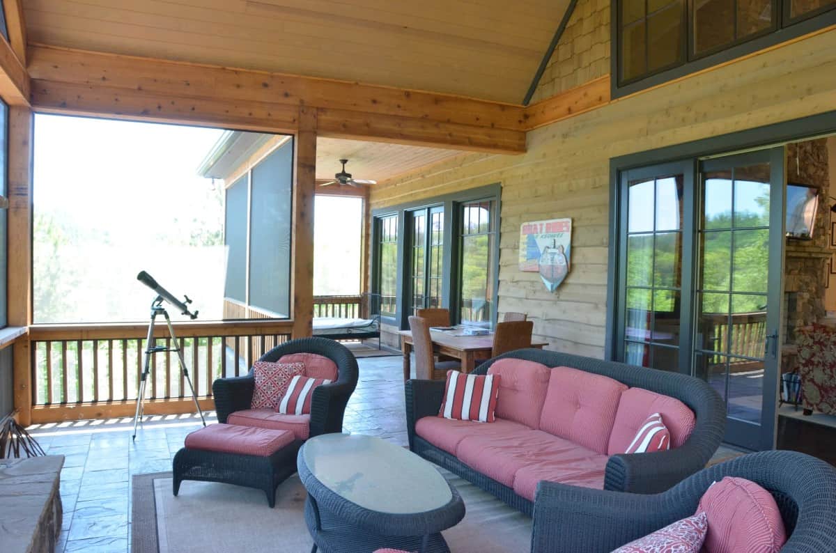 The screened porch is filled with cushioned wicker seats and a matching coffee table.