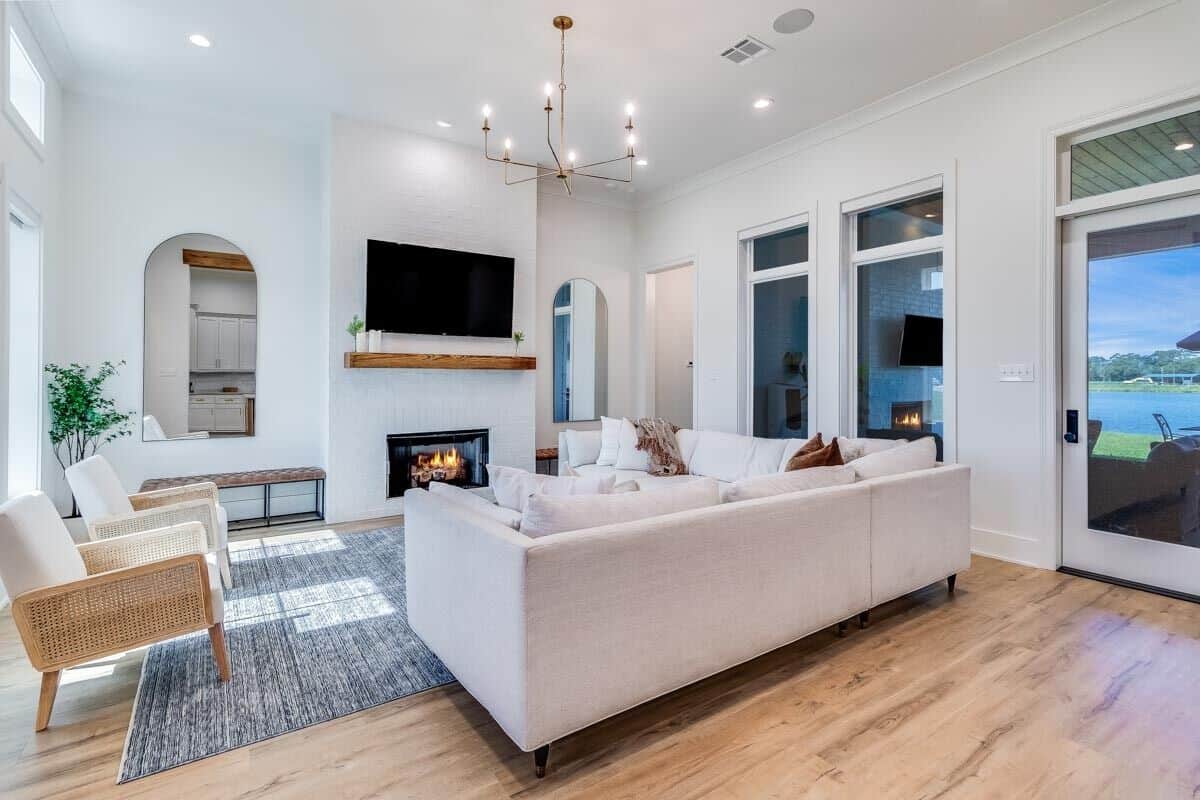 The living room has comfy seats, a large TV, and a fireplace flanked by benches and arched mirrors.