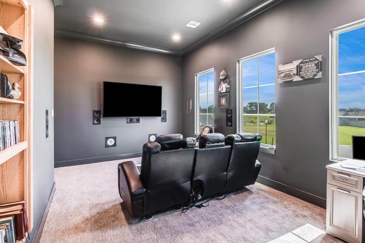 Media room with carpeted floor, black recliners, and a large TV.
