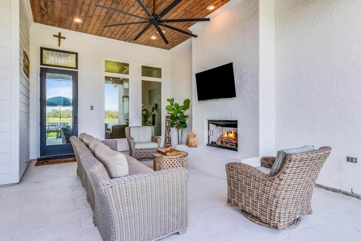 Outdoor living with wicker seats, a matching coffee table, and a fireplace with a TV on top.
