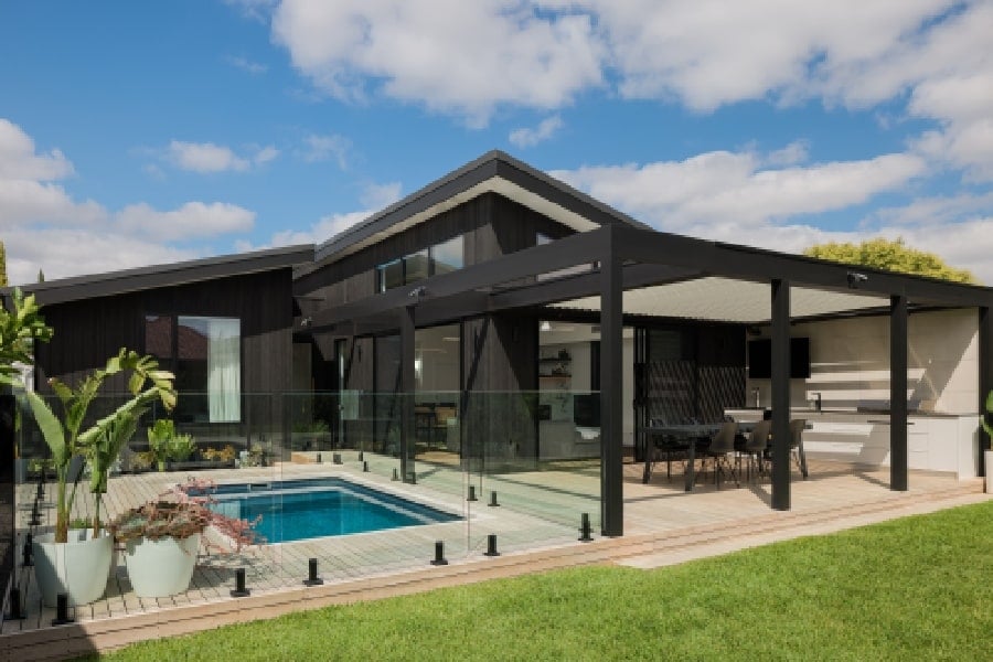 The contemporary house's exterior facade, highlighting the pergola that houses the kitchen and dining area.