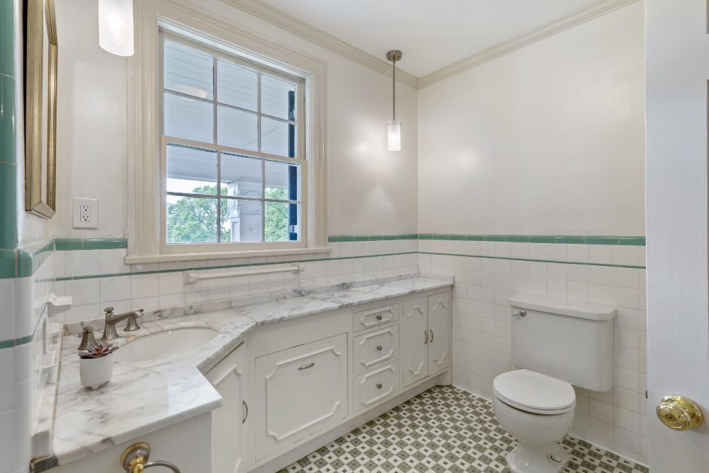 Spacious hall bath with original green and white tiles and marble vanity.