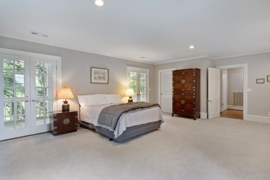 Primary suite has three closets. Dual French doors give access to the long, covered balcony.