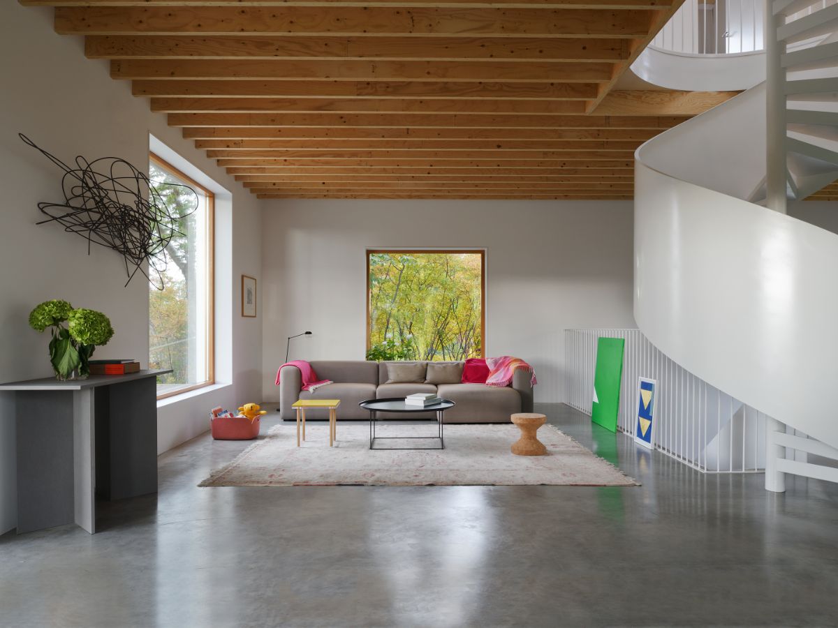The living room, which has a plywood beam ceiling with a central spiral stair under a skylight.