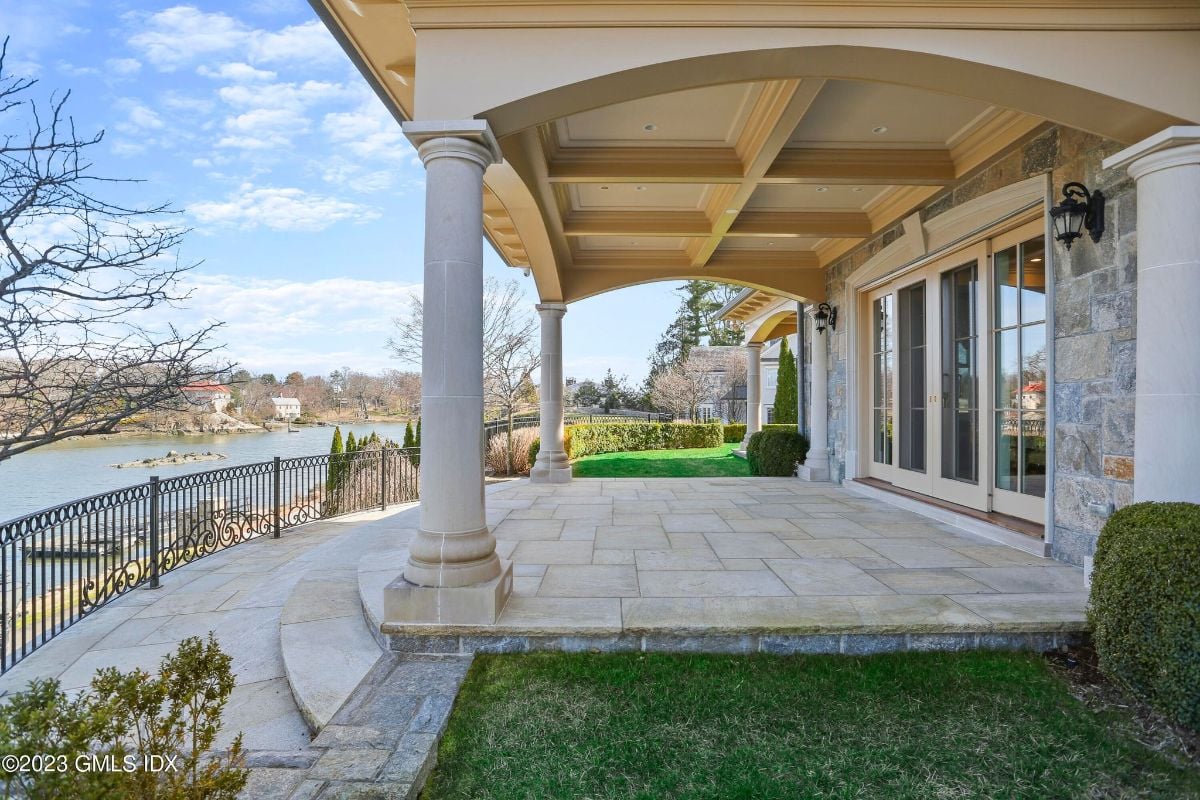The sprawling backyard of the house overlooked the serene Indian Harbor, with a sleek metal railing providing an unobstructed view of the tranquil waters.