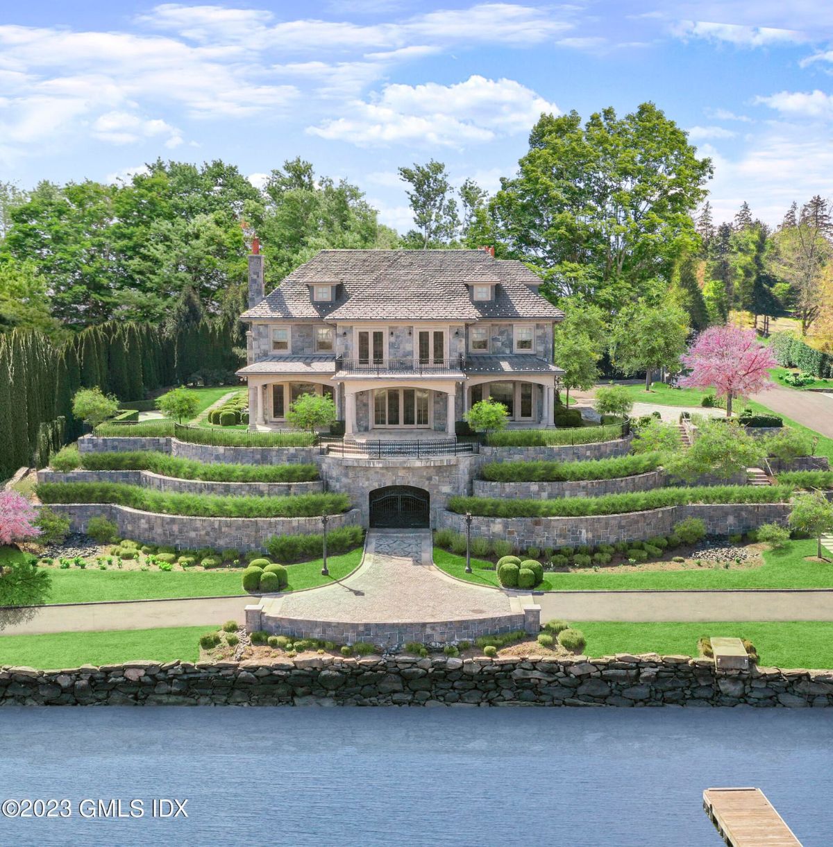 The backyard was a peaceful oasis, bordered by a sturdy stone wall that provided both privacy and a touch of rustic charm, while the breathtaking views of Indian Harbor beyond added a touch of natural beauty and tranquility to the idyllic outdoor space.