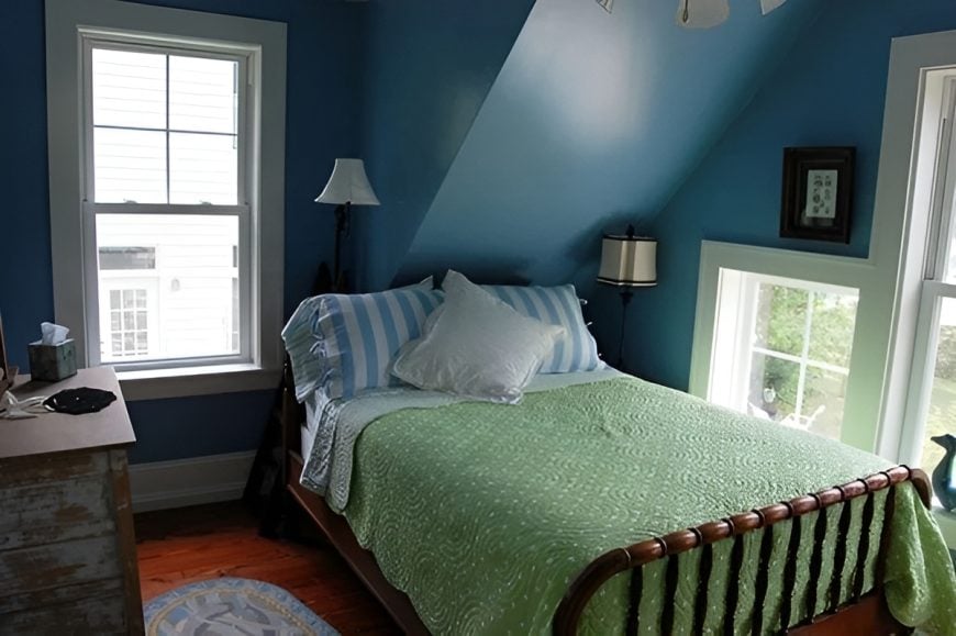 Bedroom with vaulted ceiling, blue walls, a cozy bed, and a distressed dresser.