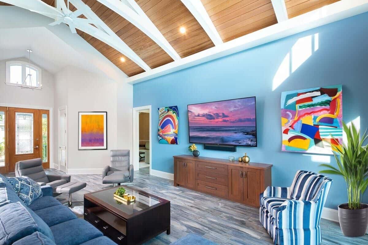 The great room has comfy seats, a large TV, and a cathedral ceiling framed with exposed trusses.