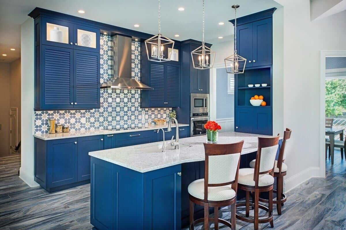 The kitchen features blue cabinetry, a decorative tile backsplash, and a breakfast bar with three seating.