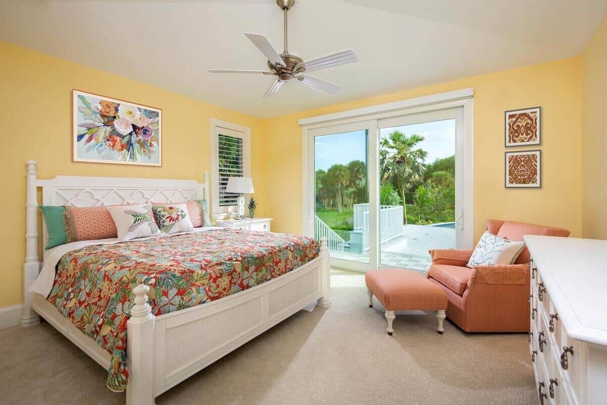 Primary bedroom with carpeted floor and bright yellow walls adorned with framed artworks.