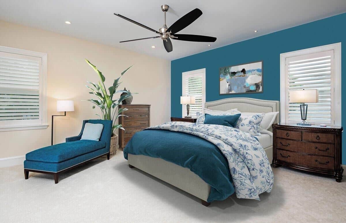 A teal accent wall reflected in the bedding and chaise lounge brings a beach vibe to this bedroom.